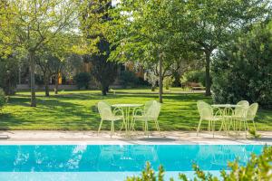 a table and chairs next to a swimming pool at Wine Resort Ledà d'Ittiri in Alghero