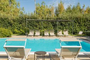 a swimming pool with chairs and a gazebo at Wine Resort Ledà d'Ittiri in Alghero