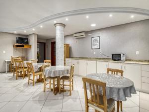 a restaurant with tables and chairs and a kitchen at Hotel Cardozo in Parobé
