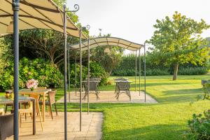 a patio with tables and chairs under an umbrella at Wine Resort Ledà d'Ittiri in Alghero