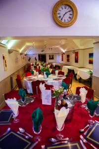 uma sala de jantar com mesas e um relógio na parede em The Beacon & Railway Hotel em Stonehouse