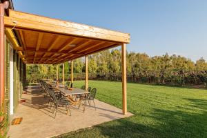 a patio with a table and chairs under a wooden pergola at Wine Resort Ledà d'Ittiri in Alghero