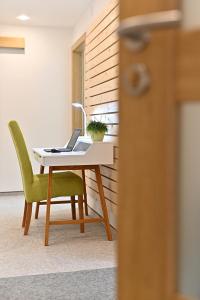 a desk with a laptop and a green chair at Apartmán 5FIVE in Prešov +19 photos