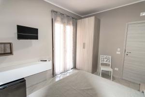 a white bedroom with a bed and a television at elegance b&b in Cariati