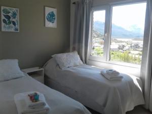 two beds in a room with a large window at Mirador del Bosque Aparts in El Chalten