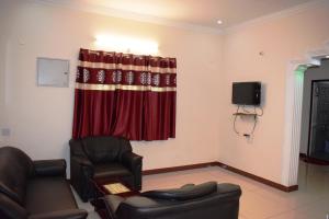 a living room with two chairs and a red curtain at White Tulip Residency in Puducherry
