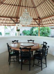 a dining room table with chairs and a chandelier at Villa Wantilan Putih in Sanur