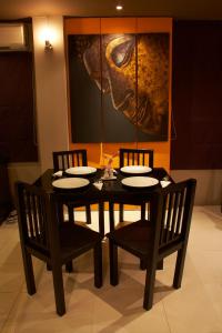 a dining room table with chairs and a painting on the wall at The Grand Pinnacle Bangkok Airport in Lat Krabang