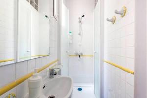 La salle de bains blanche est pourvue d'une douche et d'un lavabo. dans l'établissement Apartamento La Latina I, à Madrid