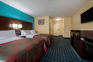 a hotel room with two beds and a flat screen tv at Ramada by Wyndham Groton in Groton
