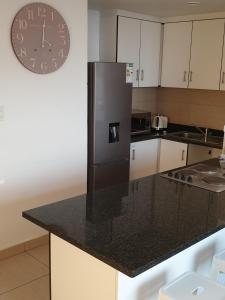 a kitchen with a black refrigerator and a clock on the wall at 904 Tenbury Beach Apartment in Durban