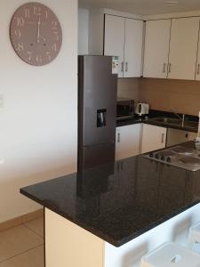 cocina con nevera negra y reloj en la pared en 904 Tenbury Beach Apartment, en Durban