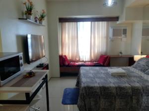 um quarto com uma cama, uma televisão e um sofá em JDT's Condo at Horizons 101 Cebu em Cebu