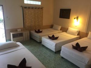 una camera d'albergo con tre letti e una finestra di Coco's Guest House a Phi Phi Don