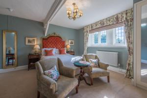 a bedroom with a bed and two chairs at Rushton Hall Hotel and Spa in Kettering