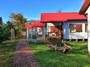 une maison avec un toit rouge et un chemin en briques dans l'établissement OW Plaża Klub domki, à Dziwnów