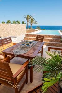 a wooden table and chairs on a deck with the beach at Villa del Mar Esquinzo Jandia Fuerteventura in Playa Jandia