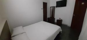 a bedroom with a white bed and a television at Hotel Acapulco in Girardot