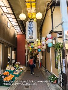 een vrouw die door een straat loopt met ballonnen die aan een gebouw hangen bij Kyoto Miyabi Inn in Kyoto