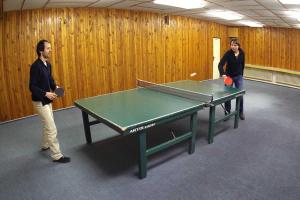 two men playing ping pong in a room with a table at Horský Hotel Neptun in Malá Morávka