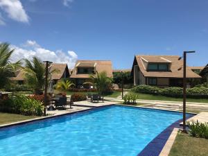 a swimming pool in front of a house at Charmoso Flat Nui Supreme - Térreo in Porto De Galinhas