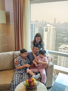 Shangri-La The Fort, Manila في مانيلا: امرأة وثلاثة أطفال يجلسون على أريكة في غرفة المعيشة