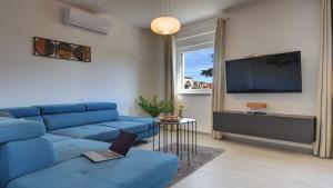 uma sala de estar com um sofá azul e uma televisão em Exclusive City Apartments em Pula