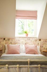 a bedroom with a bed with a window with a plant at Mill Green Cottage, On site Pools & Spa access in Somerford Keynes