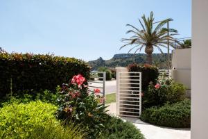 a garden with a gate and flowers and a palm tree at Hotel Nautilus in Cagliari