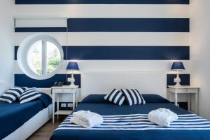 two beds in a room with blue and white stripes at Hotel Nautilus in Cagliari