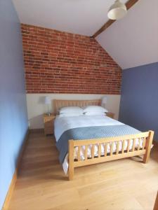 a bedroom with a bed and a brick wall at Blashford Manor Farmhouse Holiday Cottage - The Shire Cottage in Ellingham