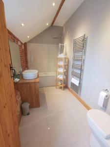 a bathroom with a tub and a sink and a toilet at Blashford Manor Farmhouse Holiday Cottage - The Shire Cottage in Ellingham