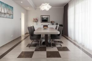 a dining room with a white table and black chairs at Luxury Rooms Vila Carissa in Malinska
