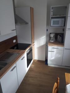 a small kitchen with white cabinets and a wooden floor at Appartement Sonnenschein in Schladming