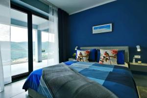 ein blaues Schlafzimmer mit einem Bett und einem großen Fenster in der Unterkunft Apartment Vanilla II with beautiful Seaview in Rabac