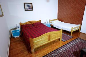 een slaapkamer met een houten bed en 2 kleine bedden bij Apartman Carpe Diem in Zaječar