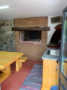 a kitchen with a brick fireplace and a wooden table at Casa do Ribeiro Frio in Santana