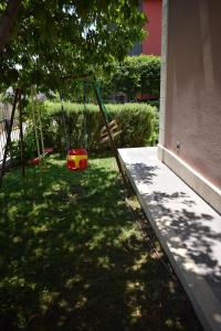 um parque infantil num quintal com um baloiço em Apartments Bazina em Kaštela