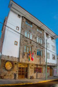 un edificio con dos banderas delante en Hotel Warari, en Cusco