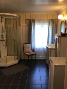 a bathroom with a shower and a chair next to a window at Bjørke Østre in Løten