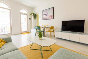 ein Wohnzimmer mit einem TV, einem Sofa und einem Tisch in der Unterkunft Casa Ricardo BEACH Apartment in Morro del Jable