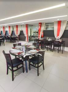 a dining room with tables and chairs and red curtains at Maktub Hotel in Floriano