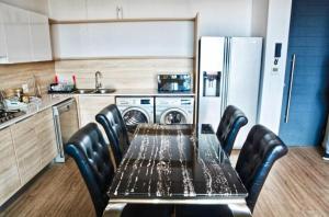 a kitchen with a table with chairs and a refrigerator at Matrix Luxury Apartments Century City, Cape Town in Cape Town