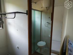 a bathroom with a toilet and a glass shower door at Recanto da Nina in Maresias