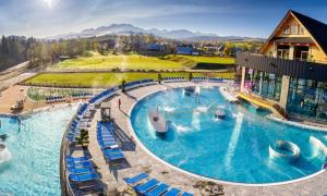 a large swimming pool with blue chairs in a resort at Ubytovanie pod Skalkou in Dolný Kubín
