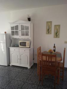 cocina con armario blanco, mesa y microondas en Apartamento MINI 1, en Puerto Naos