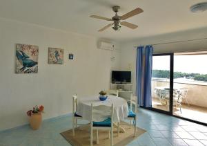 a dining room with a white table and chairs at Apartments Eufemija in Rab