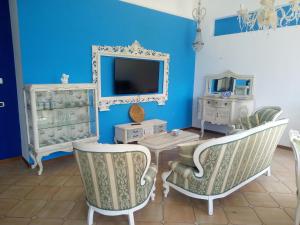 a blue room with two chairs and a table and a tv at Villa sullo stretto in SantʼAgata