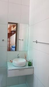 La salle de bains blanche est pourvue d'un lavabo et d'un miroir. dans l'établissement Estilo Residence II, à São Lourenço