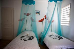 2 Betten in einem Zimmer mit blauen Vorhängen in der Unterkunft Bungalow Vanille Gite Tifigue in Saint-François